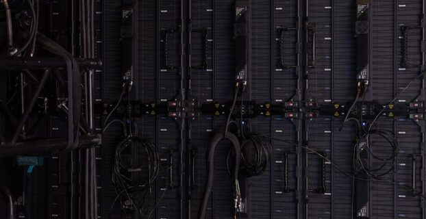 Rear view of a large video display wall with cables and control modules