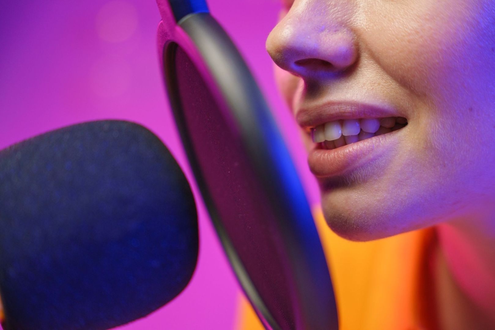 Close-up of a speaker talking into a studio microphone and pop filter