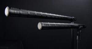 Two shotgun microphones mounted on stands against a dark background
