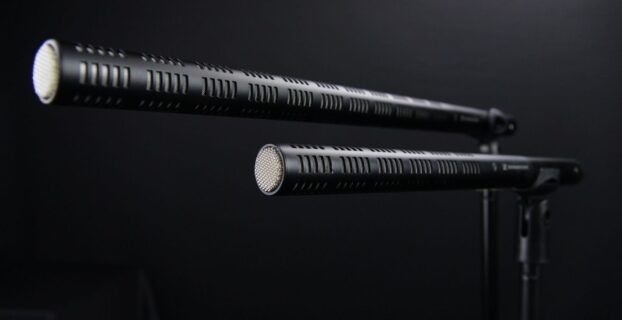 Two shotgun microphones mounted on stands against a dark background